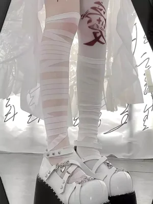 Close-up of layered sheer white bandage wrap design on thigh-high lolita socks paired with white platform Mary Jane shoes and red thigh tattoo accessory