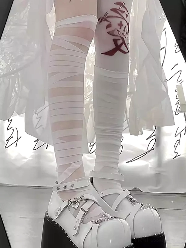 Close-up of layered sheer white bandage wrap design on thigh-high lolita socks paired with white platform Mary Jane shoes and red thigh tattoo accessory