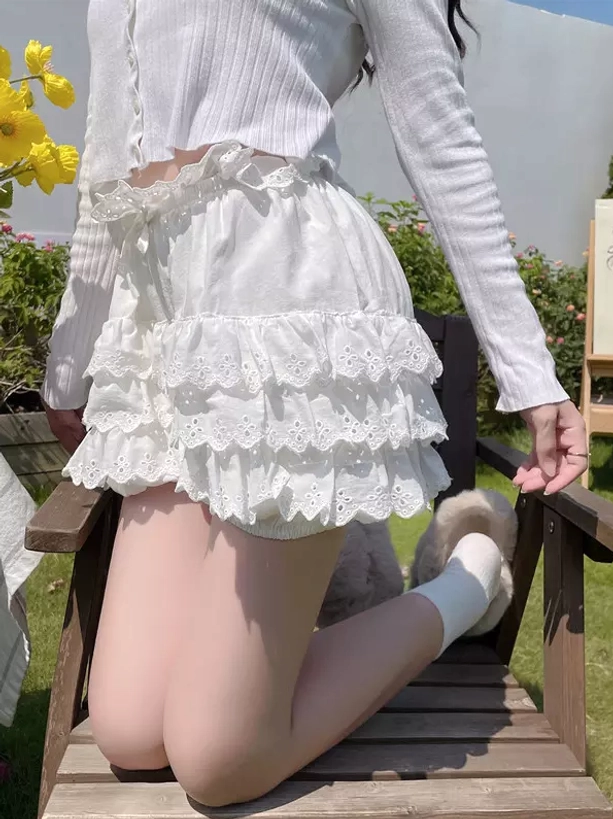 Back view of white ruffled bloomers showcasing multi-tiered lace ruffles and ruffled elastic waistband in outdoor garden