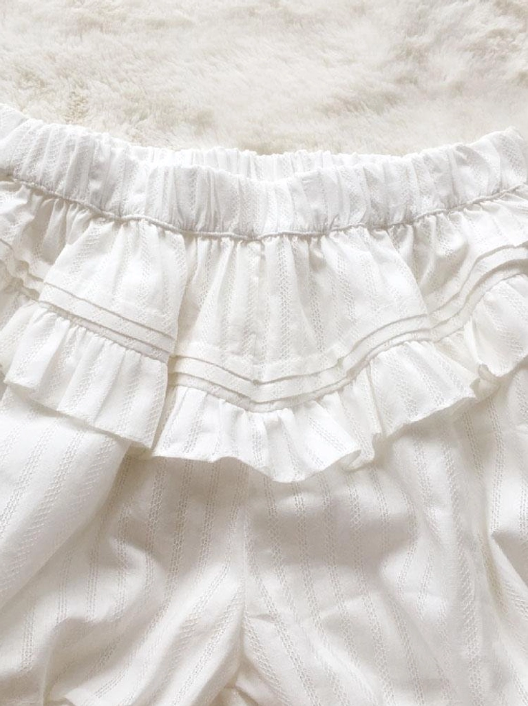 Close-up detail of elastic ruched waist with double ruffle trim and jacquard striped fabric texture