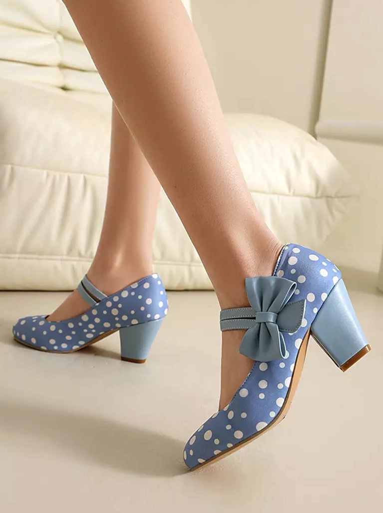 White polka dot Mary Jane lolita pumps with dark blue bow strap and block heel on model's feet - side profile view
