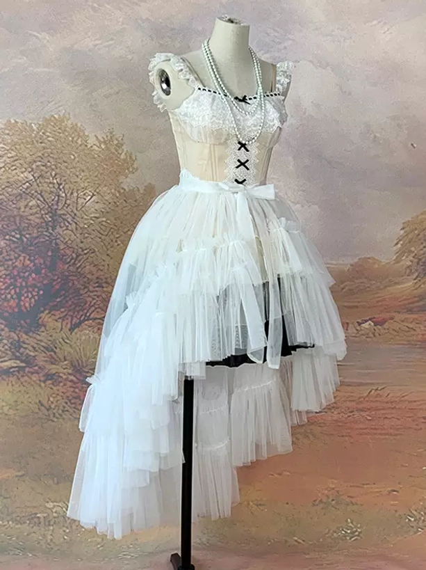 White tiered high-low tulle lolita skirt with burgundy train and lace corset top displayed on dress form with pearl accessories vintage background