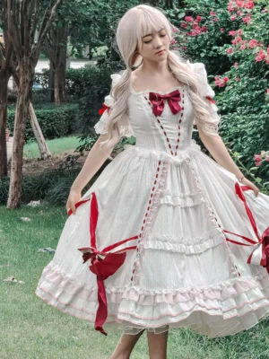 White classic lolita dress with wine red bows and ruffled skirt front view on model in outdoor garden setting