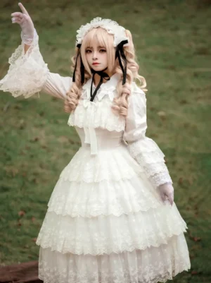 White classic lolita jsk dress with tiered lace skirt and ruffled details worn by blonde model in outdoor garden setting