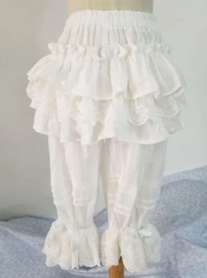 White cotton Lolita shorts with multi-layer lace trims and ruffled cuffs adorned with tiny bows, displayed on dress form, classic Japanese Lolita fashion bottoms with elastic waistband and striped woven texture