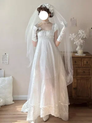 White empire waist sweet lolita fairy dress with beaded tulle, short puff sleeves, and square neckline - front full-body view on model with floral hair accessory and veil