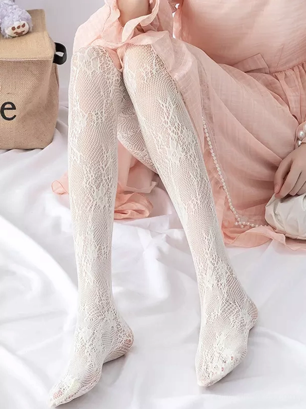 White lace fishnet embroidered tights sitting pose on bed with pink ruffled outfit showing delicate floral pattern