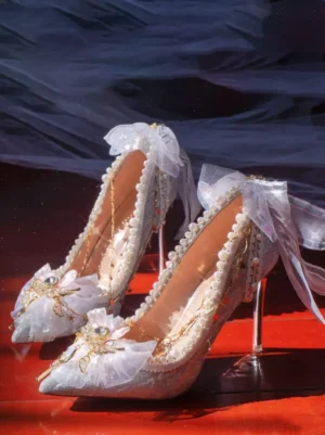 White glitter pointed stiletto lolita bridal heels with pearl trim tulle bow and gold chain details overhead view