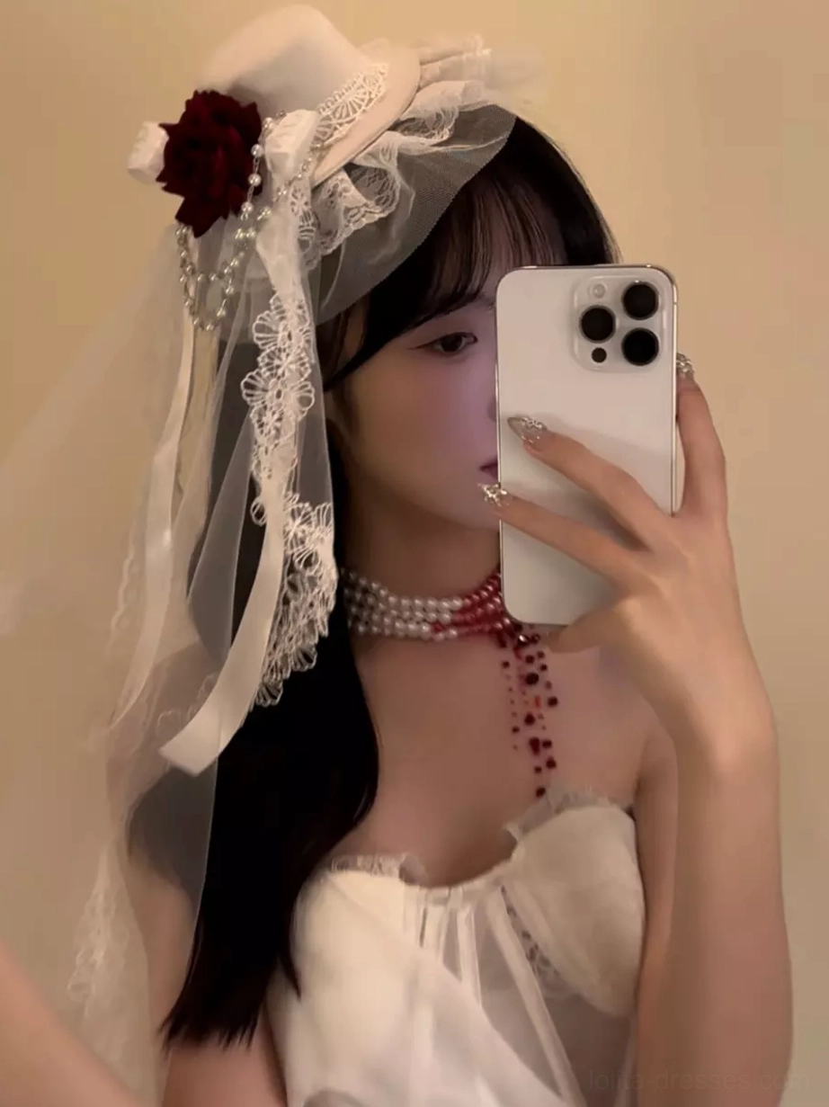 White Gothic hair accessory with lace trim, long veil, and red rose in side selfie view on model with long dark hair
