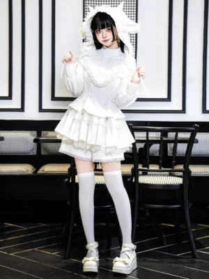 White gothic lolita dress with cat ear hood and tiered ruffle skirt worn with thigh-high socks, full body front pose in dining area setting