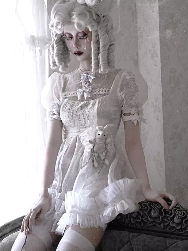 White Gothic Lolita Dress Side Portrait View - Model Seated on Vintage Sofa with Plush Rabbit and Sheer Lace Yoke Detail