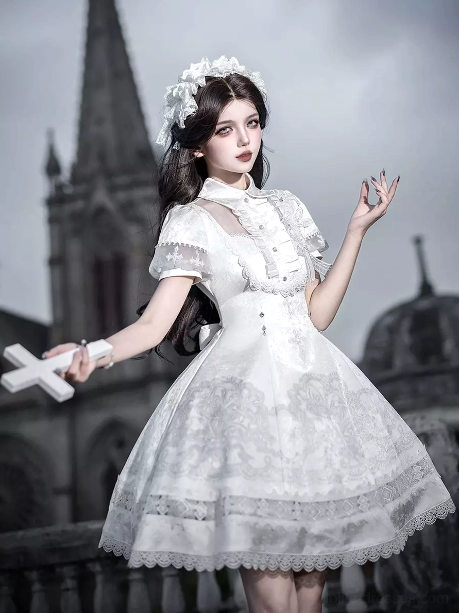 White Gothic Lolita JSK dress three-quarter front view showing ruffled collar trim puff short sleeves lace embroidered skirt with model holding cross prop