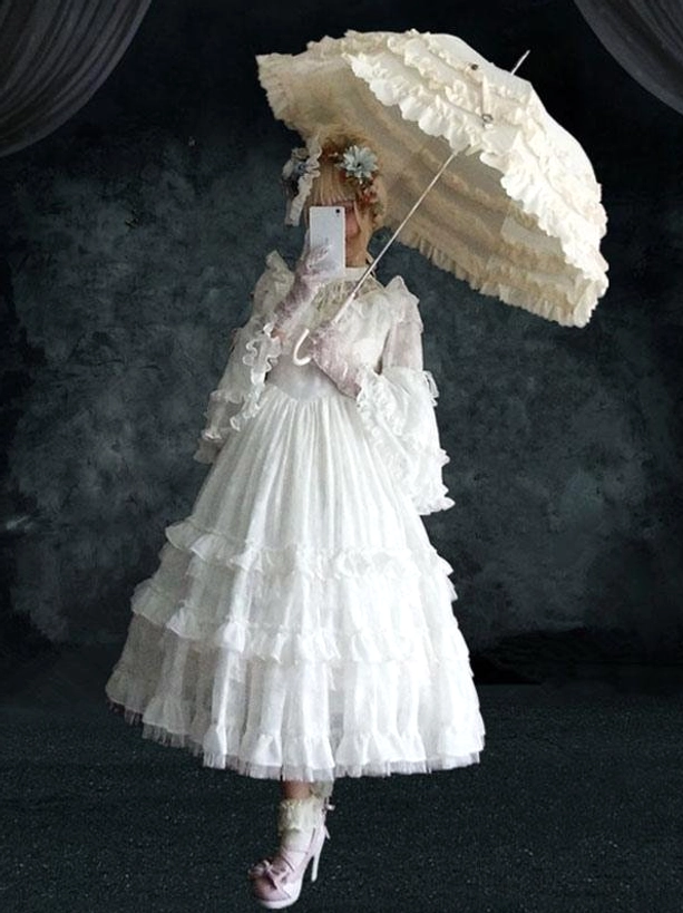 White Gothic Lolita midi dress half-side view model with ruffle parasol pink accessories tiered skirt long flare sleeves