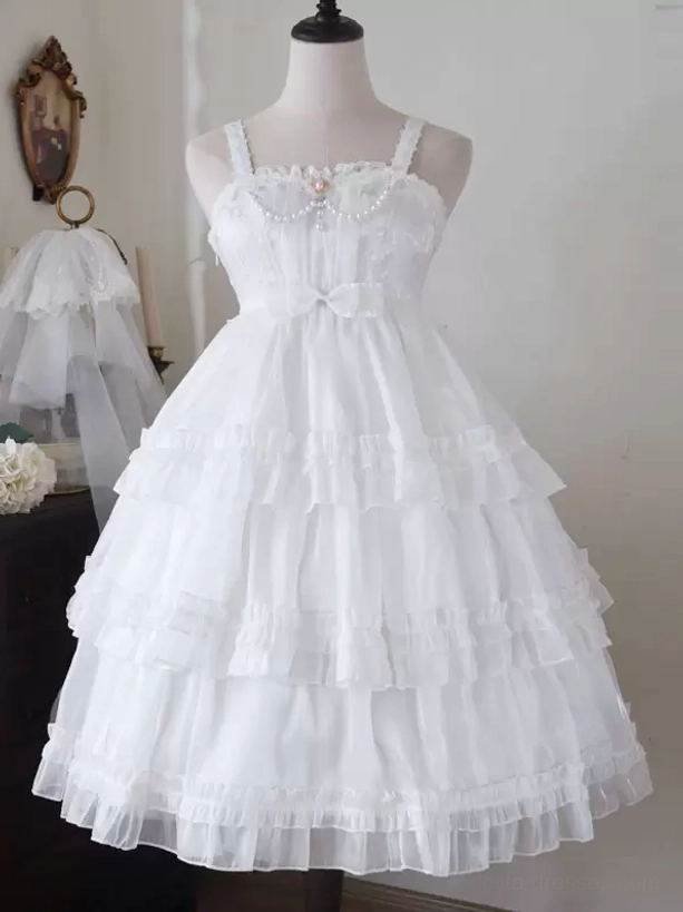 White sweet Hime Lolita jumper dress front full view with delicate lace neckline, decorative waist bow, and layered ruffled tulle skirt in vintage interior room