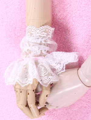 Side profile view of white lace Lolita arm cuffs with pink bow accent on paired wooden mannequin hands, showcasing ruched lace construction
