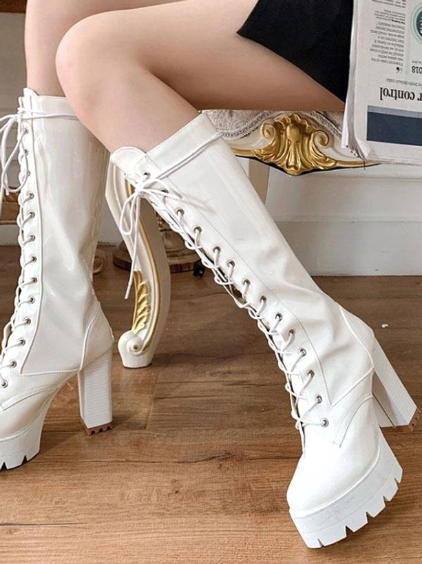 White mid-calf lace-up platform boots on female model with vintage indoor setting, showing front lace closure and high chunky heel design for lolita footwear