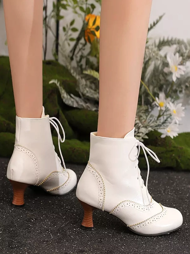 White Lolita ankle boots displayed on female legs showing side and rear views, featuring gold decorative stitching, lace-up closure system, and authentic vintage aesthetic against outdoor floral backdrop