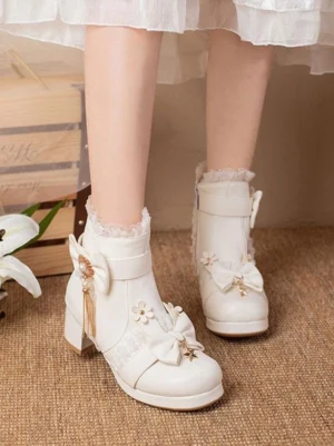 White lolita ankle boots side view with floral decor and tassel bow, model in white lolita dress with side zipper closure detail