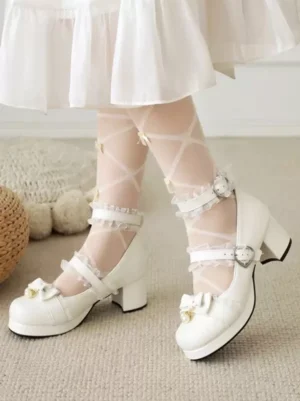 White Lolita block heel Mary Jane pumps with pearl bow ornament and dual ankle straps, side view of model's legs with sheer crisscross stockings and white skirt hem