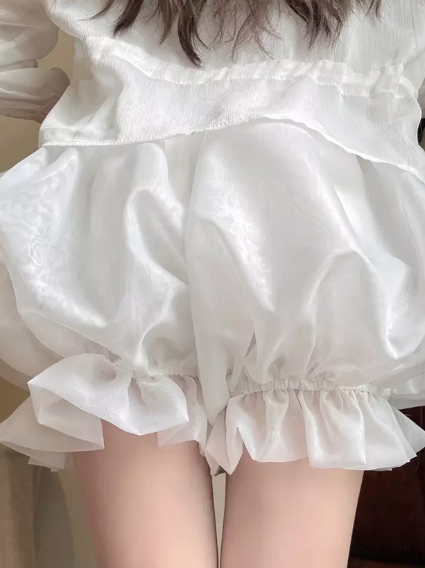 Side profile of white lolita bloomer shorts displaying voluminous pumpkin shape ruffled hem satin-like texture and elastic waist design