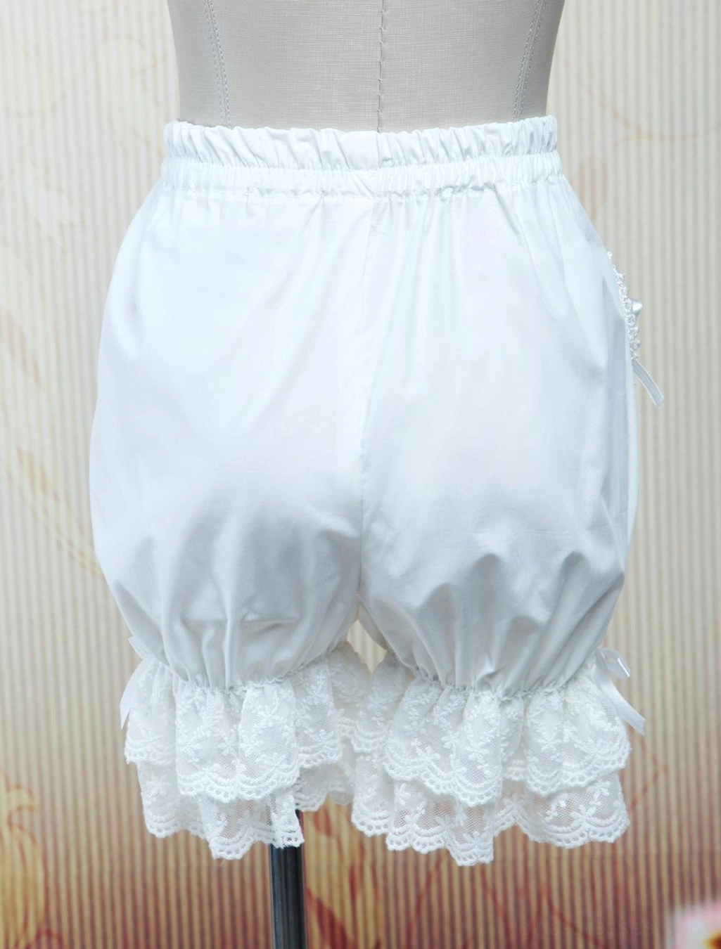 White lolita bloomers rear back view displaying ruffled lace hem and side bow details on dress form