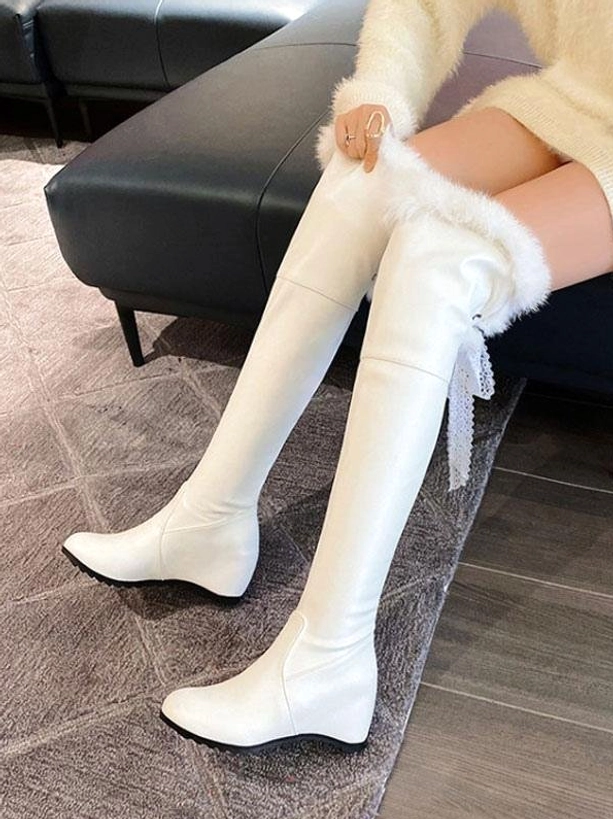 white over-the-knee lolita boots with faux fur collar and lace ribbon tassel worn on model in beige knitwear indoor setting