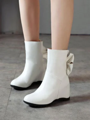 White Lolita bow ankle boots side front view with bow detail, black rubber outsole, and round closed toe, worn on model's legs