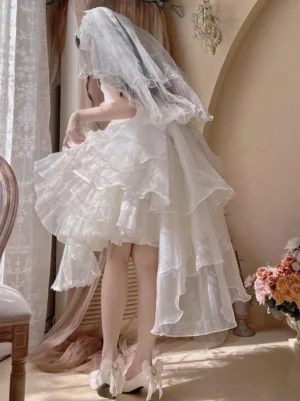 White lolita bridal veil with multi-layer ruffled tulle skirt worn by model in vintage indoor setting, rear view perspective showcasing cascading veil layers and bow-knot heel details