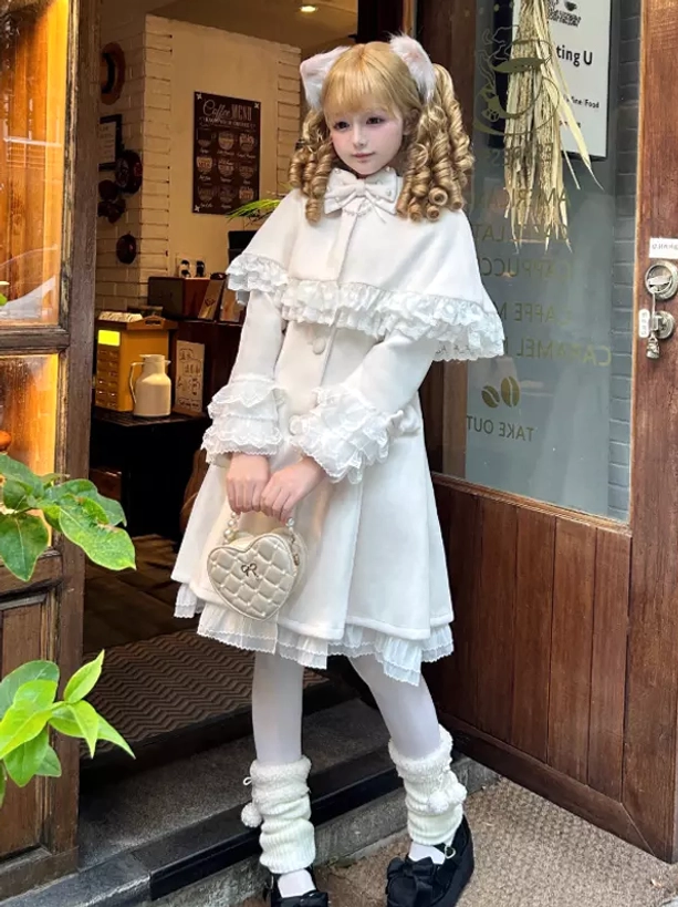 White sweet lolita cape coat front view with lace trimmed removable cape ruffled collar and leg warmers indoor cafe styling
