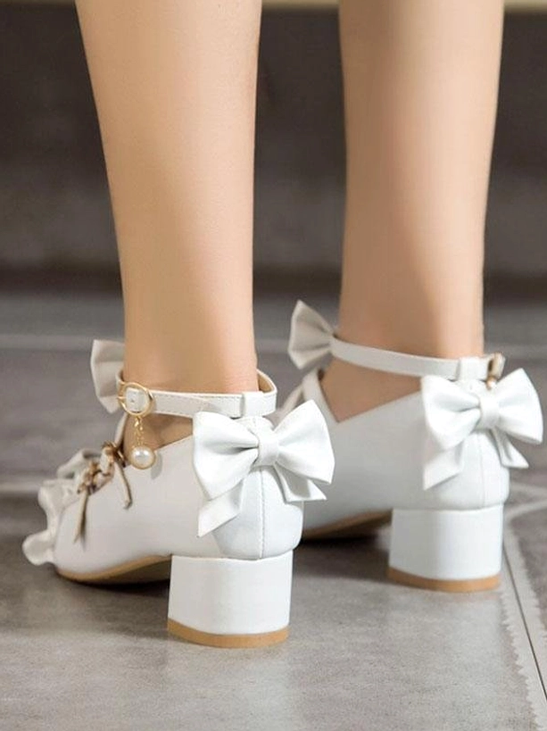 White lolita pumps with chunky block heel and prominent rear bow embellishment shown from back view of model's lower legs, featuring pearl accents and structured block heel construction typical of sweet lolita aesthetic