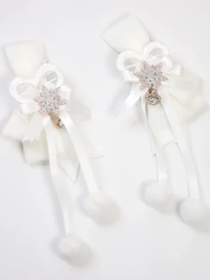 Pair of cream white Lolita hair clips with fluffy pom-pom tassels and snowflake rhinestone pendants on pure white background, flat lay top-down view showing satin bow construction