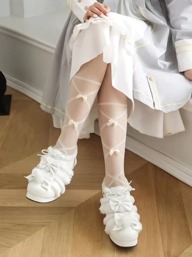 White lolita heels with multiple fluffy bows and block heel design, low angle seated leg view against white lolita outfit background
