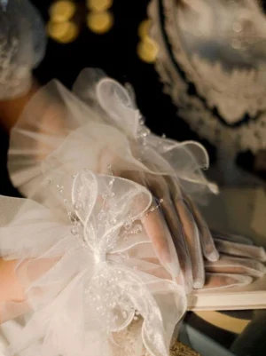 white sheer tulle lolita bow gloves with layered puffy bows and bead decorations vintage mirror bokeh background side view
