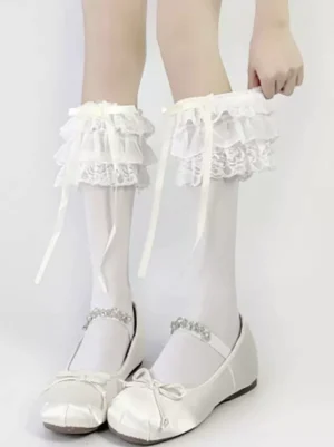 Close-up front view of white lolita mid-calf socks with multi-layer lace ruffles and satin ribbon bows, showcasing delicate ruffle texture and bow details on female model legs against clean white background