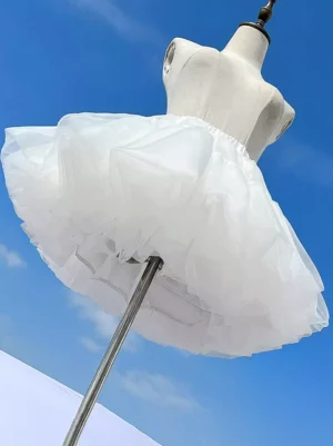 White lolita petticoat side angle view on mannequin displaying fluffy voluminous silhouette with multi-layer sheer tulle construction and elastic waistband detail against blue sky outdoor background