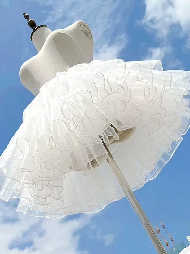 White lolita petticoat side profile view eye-level showing curved rolled ruffled skirt edge and tulle volume on mannequin
