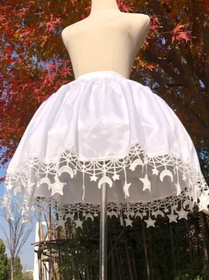White lolita petticoat with star and moon lace hem trim displayed on dress form in outdoor autumn setting with red maple trees, showing front view of flared sweet lolita underskirt silhouette