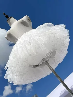 White lolita petticoat side profile view displaying fluffy bell-shaped silhouette and crinkled tulle layers on mannequin torso outdoor setting
