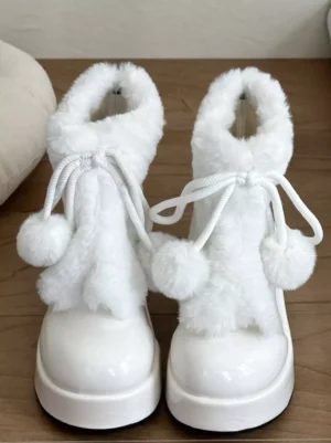 White lolita snow boots front view displaying pom-pom drawstring and patent leather round toe design