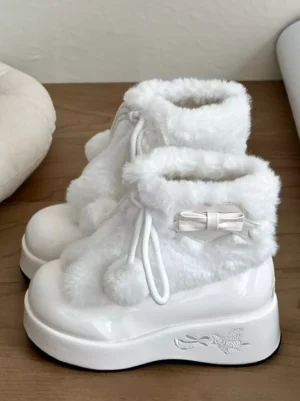 White lolita platform boots with satin bow and plush lining shown from side overhead angle on wooden desk