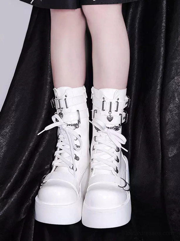 White platform combat boots worn by model with glossy leather metal buckles lace-up closure and chunky sole against dark fabric