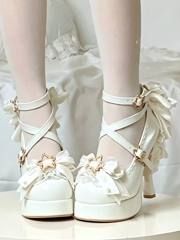 White lolita platform high heels featuring crisscross ankle straps, large decorative back bow, gold star hardware, and pearl-adorned front lace bows