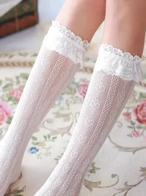 Solid white lace ruffle lolita stockings close-up frontal view of both lower legs on vintage floral printed carpet showing vertical woven lace pattern and wide frilled lace top trim
