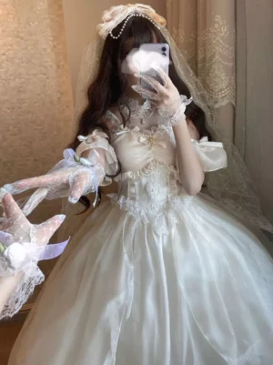 Off-shoulder white lolita wedding dress with tulle skirt, lace gloves, and pearl hair ornament worn by model with curly hair, close-up selfie view