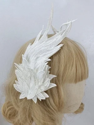 White embroidered lace wing lolita headdress worn on blonde mannequin head, side profile view showing delicate trailing wing tips and intricate embroidery detailing against light gray background
