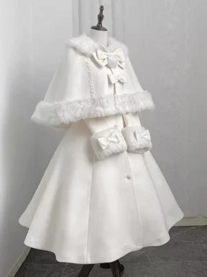 White lolita winter cape overcoat three-quarter front view on dress form displaying pearl-style buttons and dual bow accents with luxurious fur edging