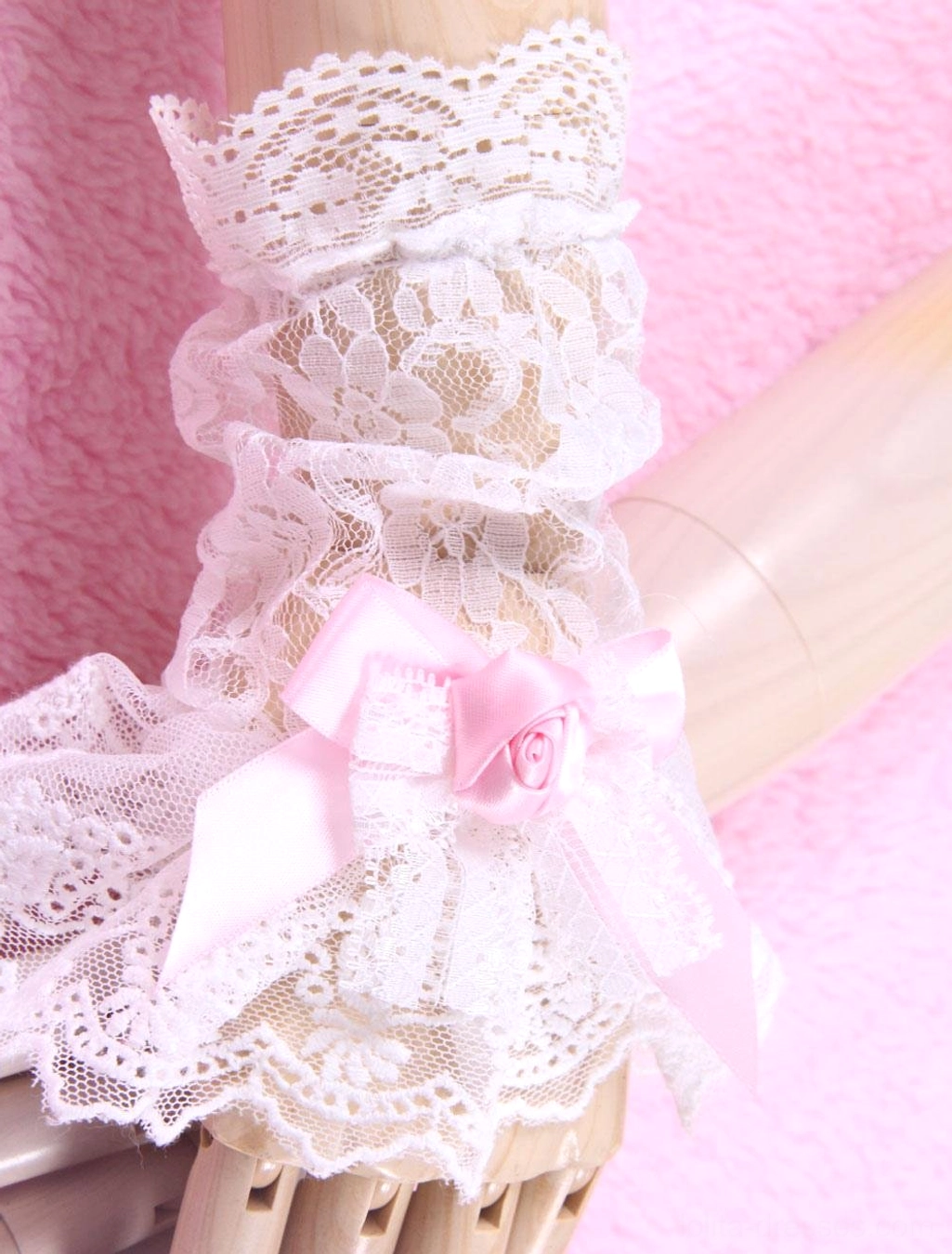 Close-up oblique view of layered floral white lace Lolita wrist cuffs with pink satin bow and rose decor on mannequin hand fine detail