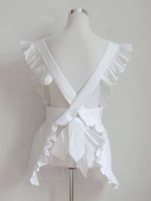 White maid lolita apron back view showing crisscross straps and decorative bow with ruffled trim details