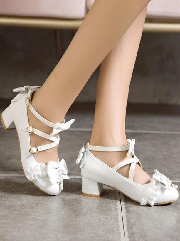 White multi-strap lolita pumps with ruffled toe cap and structured block heel shown in side front view of model's feet without socks, emphasizing cross ankle strap configuration and sweet lolita design details