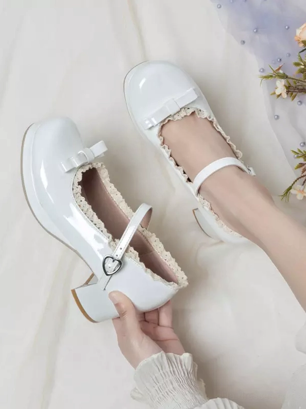 White patent leather lolita pumps top-down hand-held display ruffled trim front bow heart-shaped buckle block heel floral decorative background